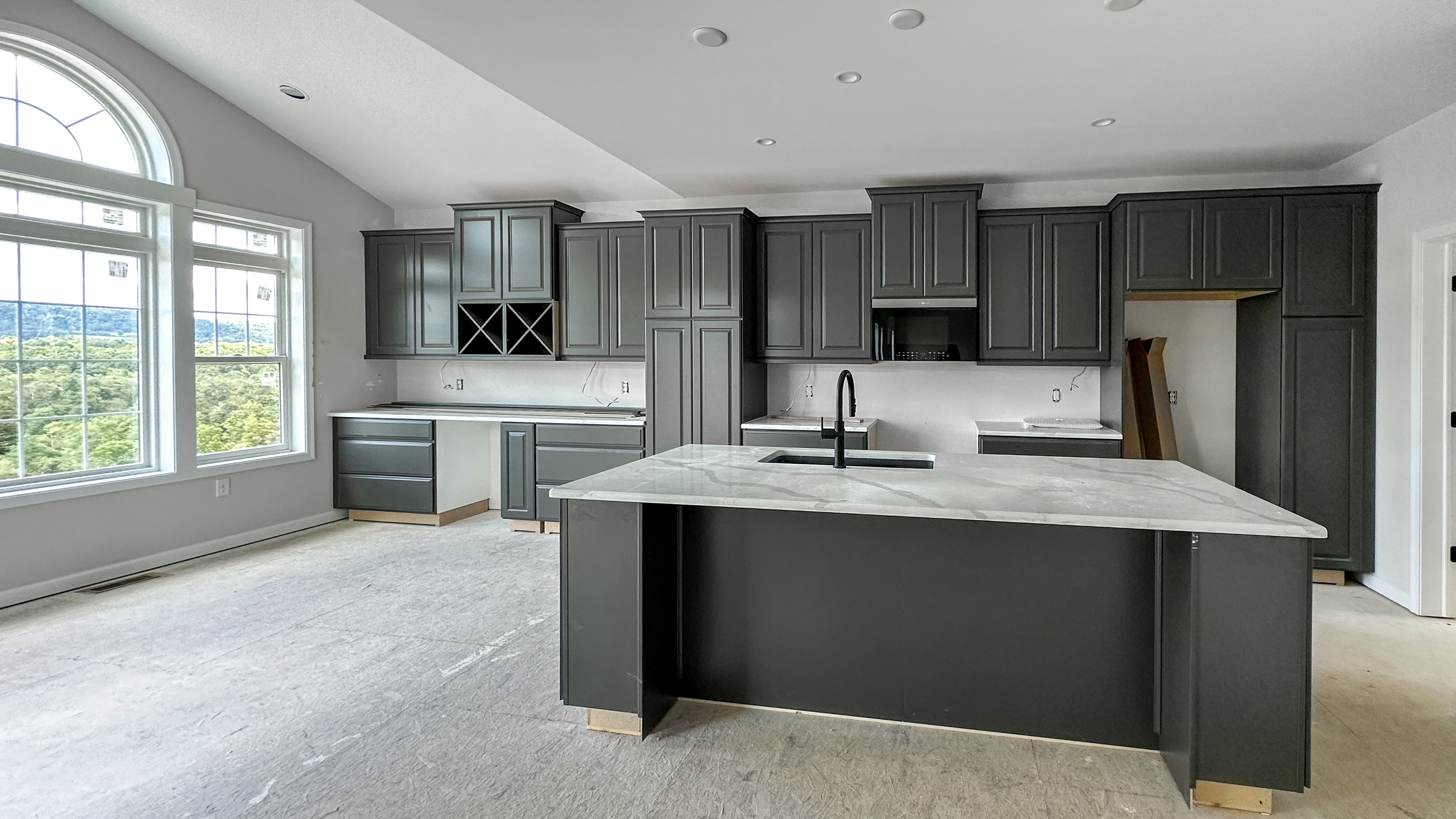 Stage 4 - Drywall and Finish Trades.jpg: Kitchen under construction with installed cabinetry and large island, preparing for countertops and final finishes.