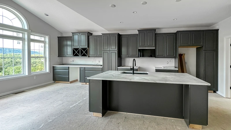 Stage 4 - Drywall and Finish Trades.jpg: Kitchen under construction with installed cabinetry and large island, preparing for countertops and final finishes.