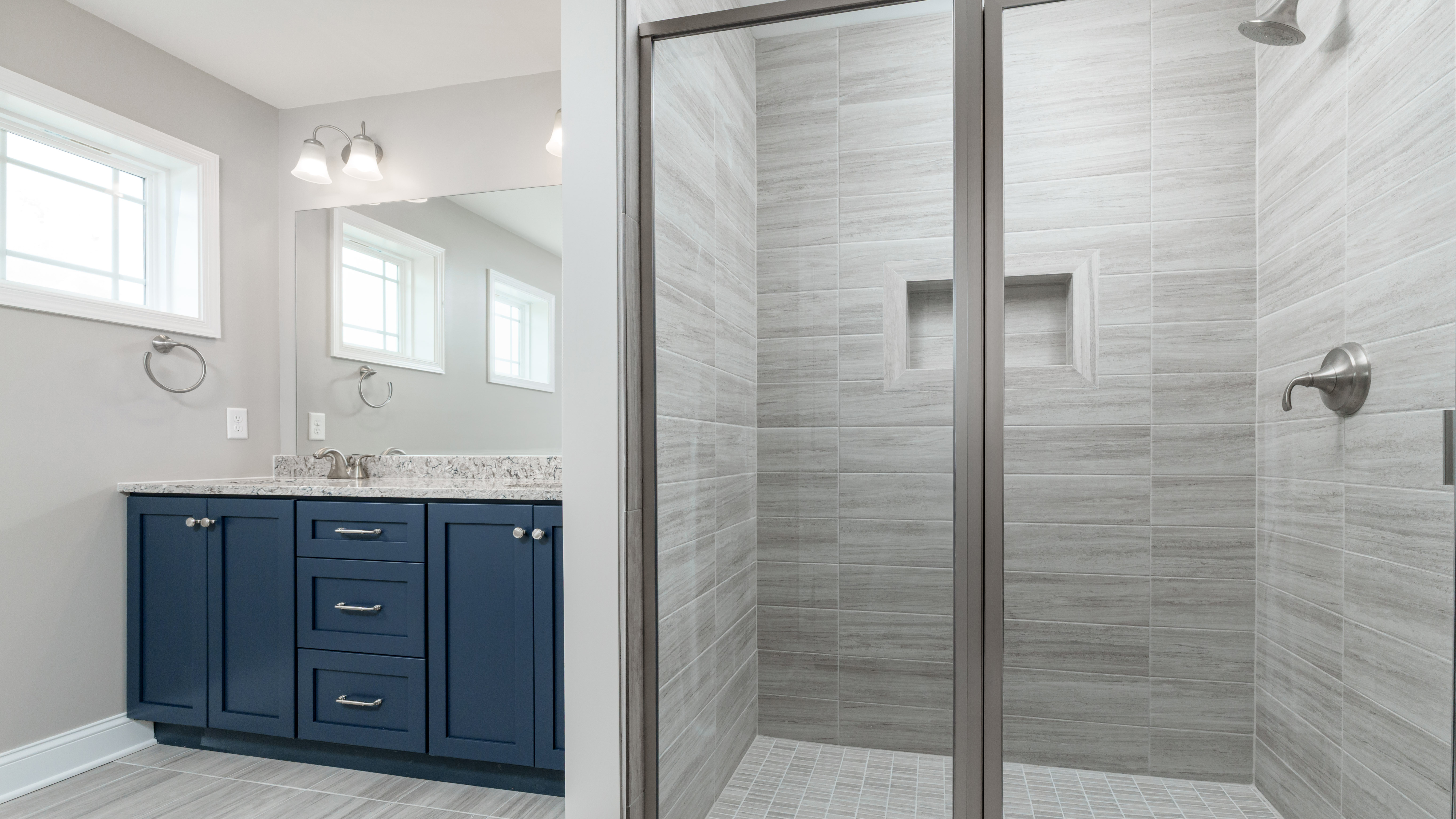 Stage 5 - Final Finishes.jpg: Finished bathroom featuring tiled walk-in shower, glass enclosure, and double vanity with modern lighting.