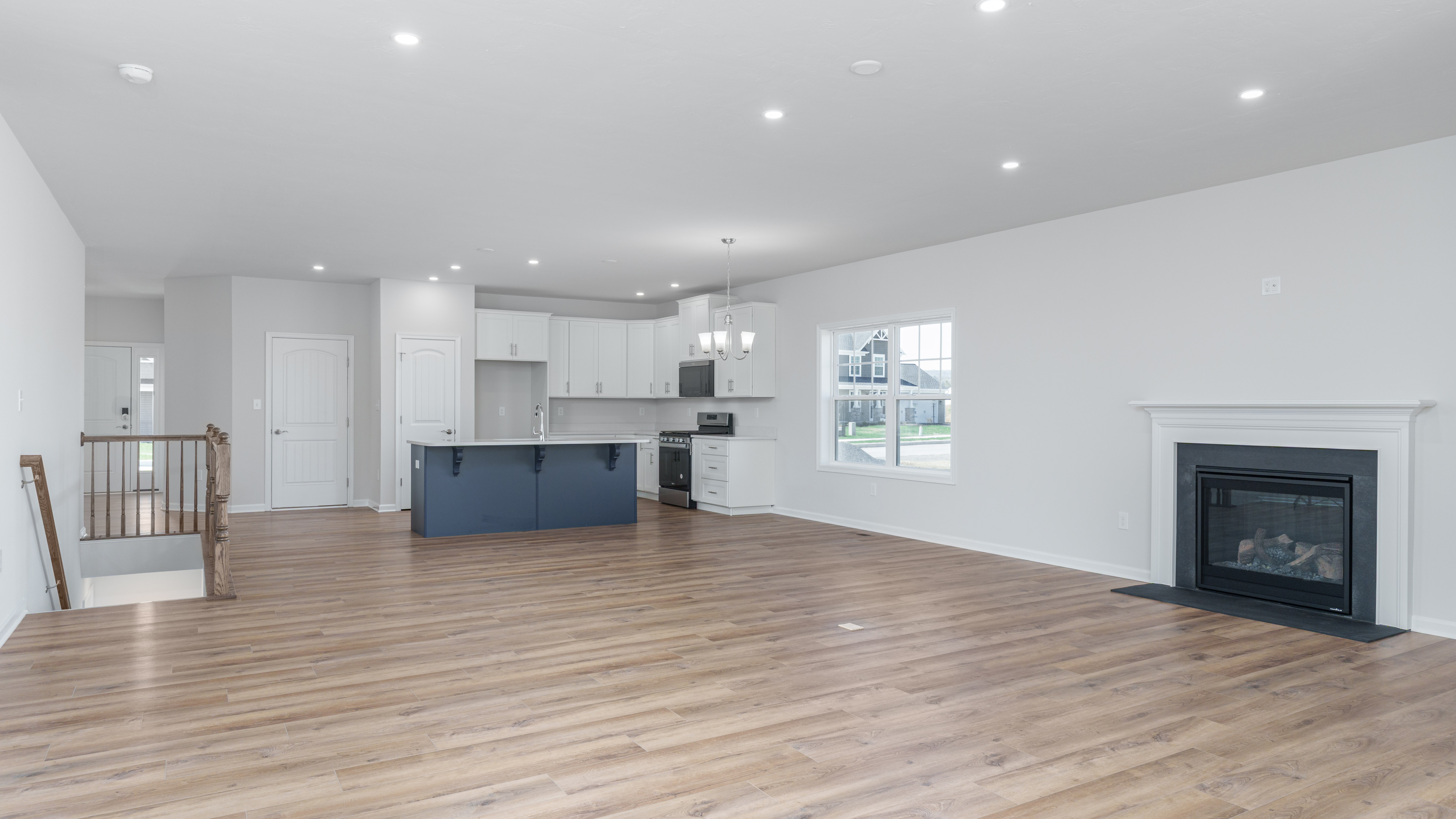 Stage 6 - Final Review and Touchups.jpg: Bright open living area with completed kitchen, vinyl plank flooring, fireplace, and final walkthrough ready space.