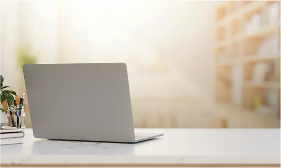 Laptop placed on a desk in a sun light lit room ready for online shopping.